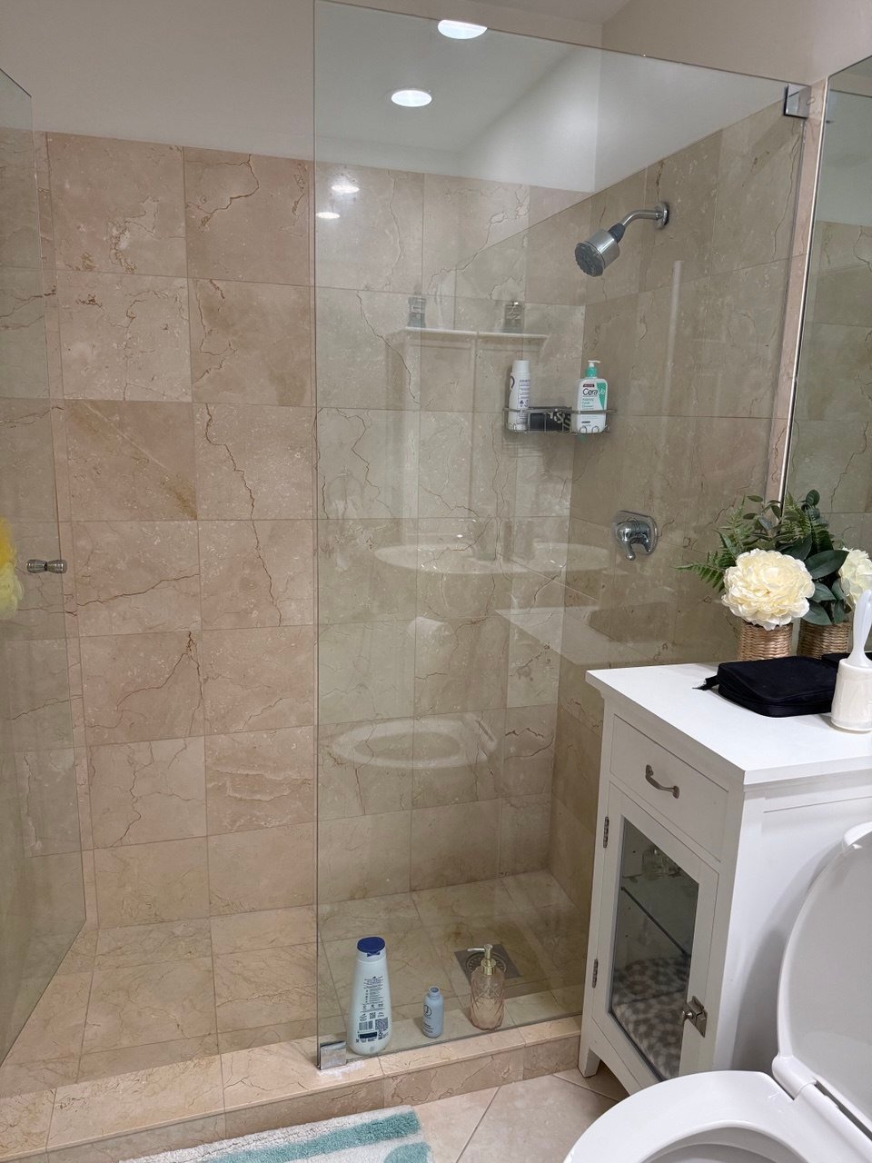 Glass shower and tiled bathroom detail in a home cleaned by Cleanantsy